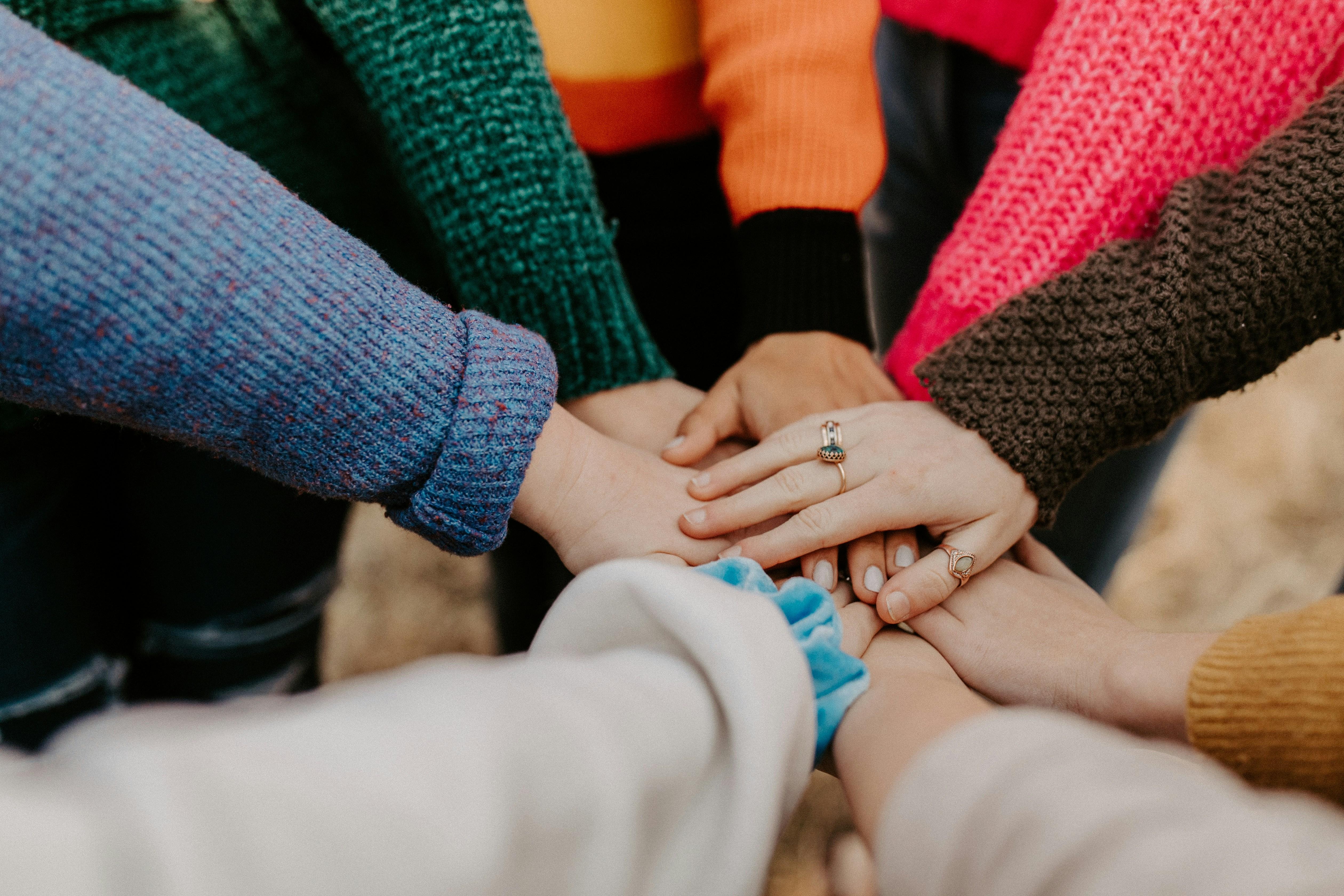 Group of people putting their hands in to suggest teamwork